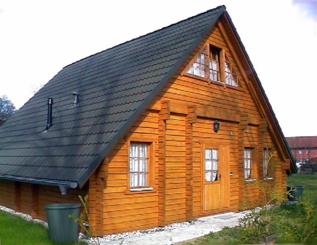 Eine traditionelle Holzhütte mit steilem Satteldach und symmetrischen Fenstern an der Vorderseite, gelegen in der malerischen Gegend des Ferienhauses Königstein.
