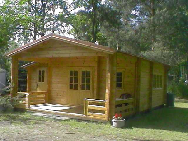 Eine Holzhütte mit einer Veranda zwischen Bäumen.